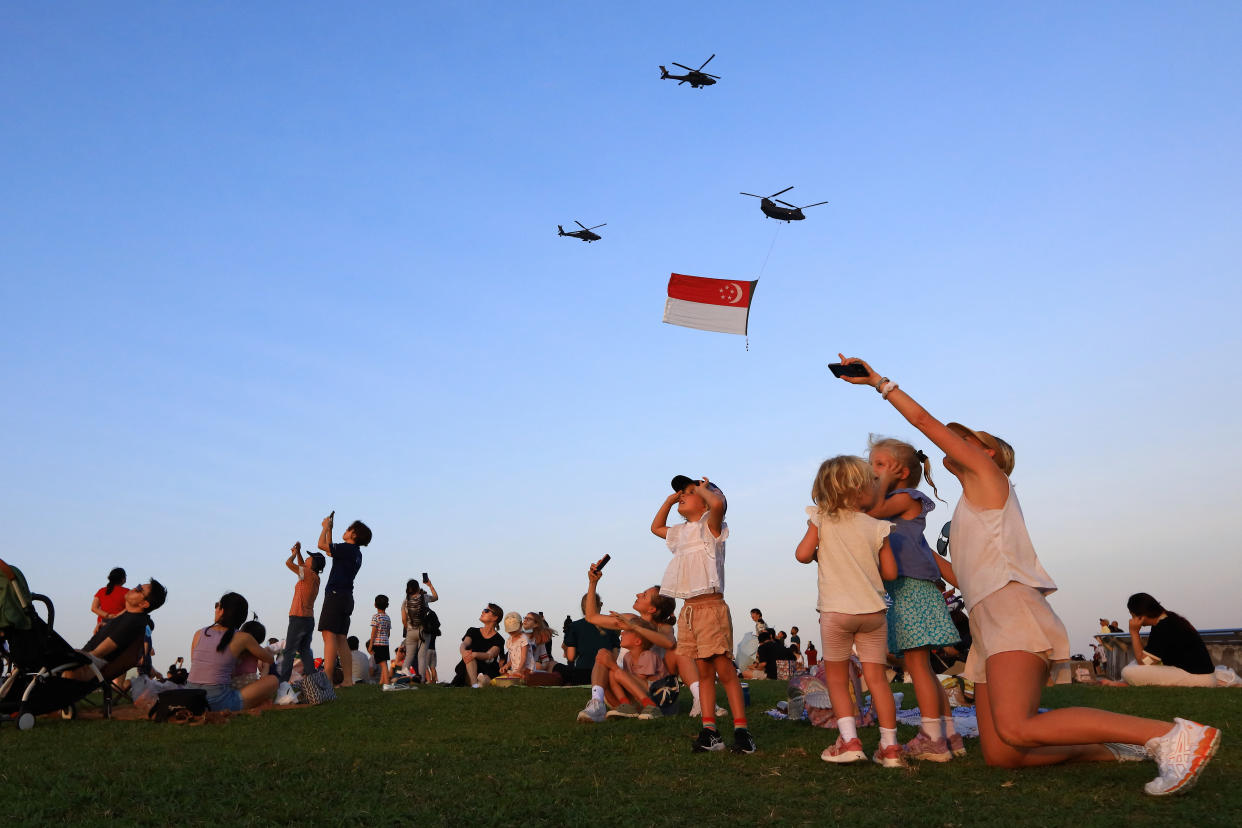 Singapore residents react and take photos during the flypast of the State Flag during the 2022 National Day Parade rehearsal.