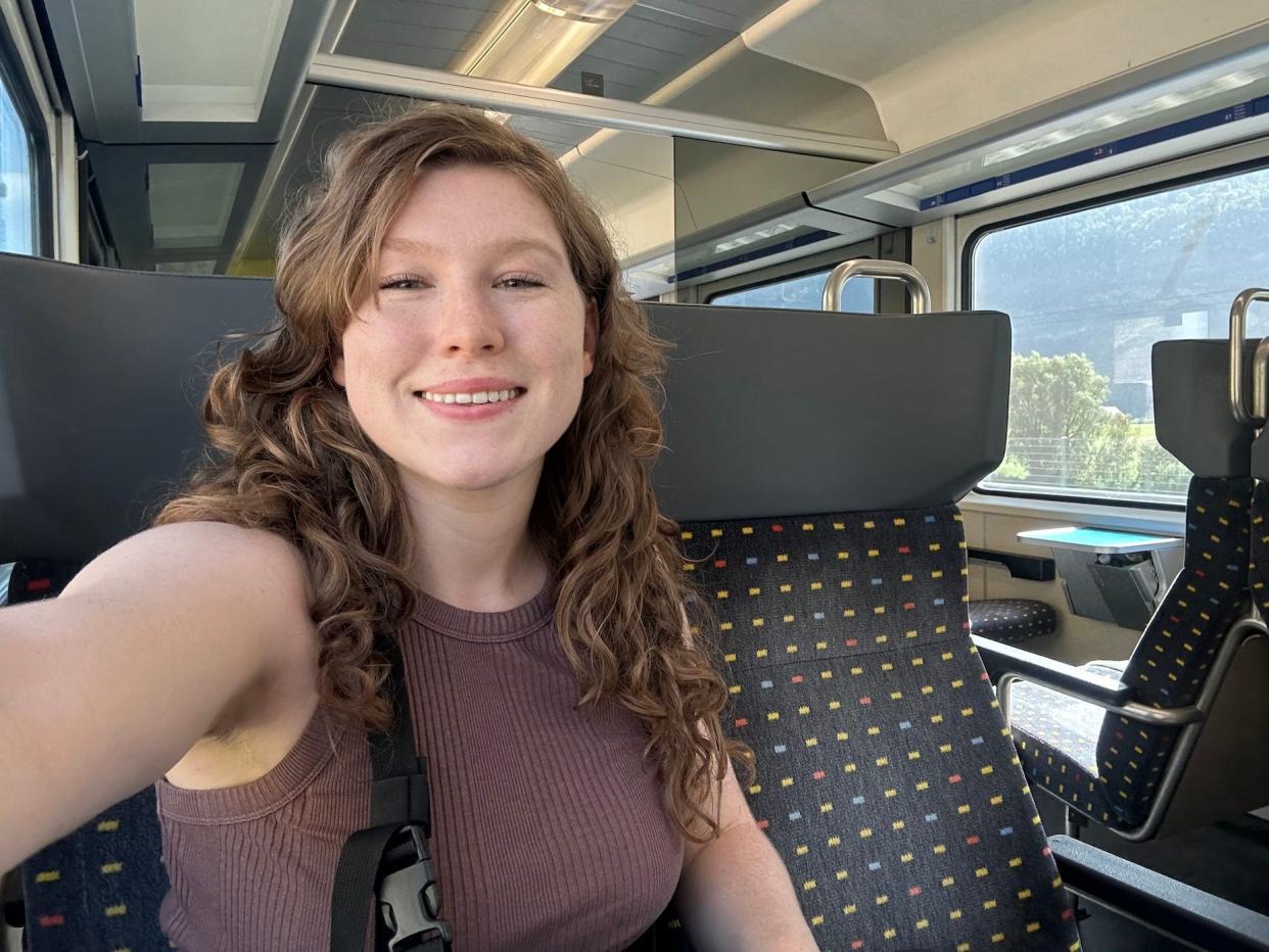 smiling woman in brown shirt sitting inside a train