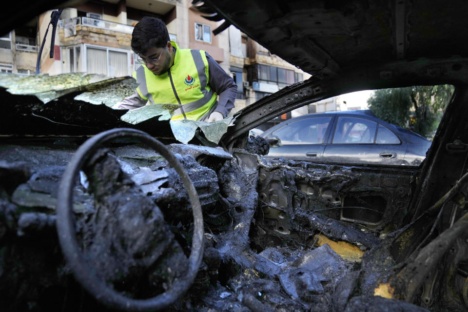 A Hezbollah Civil defense worker searches for body remains on a burned car, near an apartment building where an apparent Israeli strike Tuesday killed top Hamas political leader Saleh Arouri, in the southern suburb of Beirut that is a Hezbollah stronghold, Lebanon, Wednesday, Jan. 3, 2024. The apparent Israeli strike that killed Hamas' No. 2 political leader, marking a potentially significant escalation of Israel's war against the militant group and heightening the risk of a wider Middle East conflict. (AP Photo/Hussein Malla)