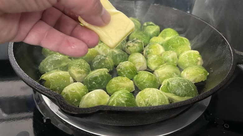 hand holding butter over pan