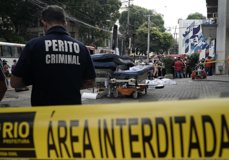 An investigator stand at the entrance of the Badim Hospital, where a fire left at least 11 people dead, in Rio de Janeiro, Brazil, Friday, Sept. 13, 2019. The fire raced through the hospital forcing staff to wheel patients into the streets on beds or in wheelchairs. (AP Photo/Leo Correa)