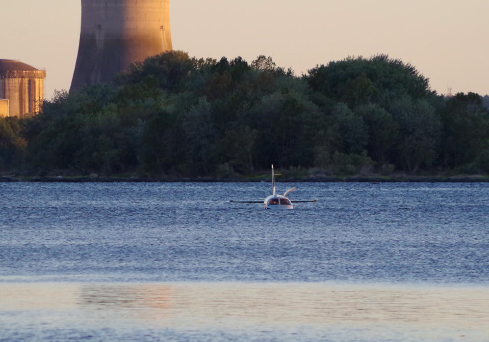 A small plane sits in in a shallow section of the Susquehanna River a few miles from the Three Mile Island nuclear power station after landing on an approach to a Pennsylvania airport, Friday, Oct. 4, 2019 near Middletown, Pa. Susquehanna Regional Airport Authority executive director Tim Edwards said the pilot and the single-engine plane's lone passenger were taken to a hospital for treatment. The Federal Aviation Administration says the two on board exited the Piper PA-46 onto a wing.(Garrett Doane/The Sun via AP)
