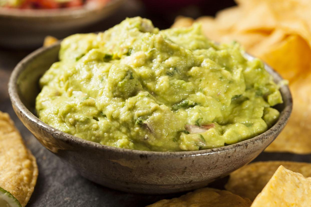 Guacamole in a brown gray stone bowl with tortilla chips