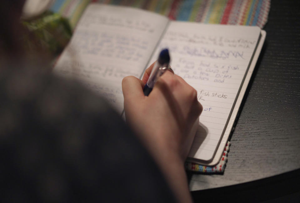 Lauren Hackney makes a note of what her 1-year-old daughter ate for dinner during a supervised visit at their apartment in Oakdale, Pa., on Thursday, Nov. 17, 2022. Lauren, 27, has attention-deficit hyperactivity disorder that affects her memory. (AP Photo/Jessie Wardarski)