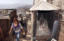 A resident walks past a religious image of the Virgin Mary after a forest fire burned several neighbourhoods in the hills in Valparaiso city, northwest of Santiago, April 13, 2014. At least 11 people were killed and 500 houses destroyed over the weekend by a fire that ripped through parts of Chilean port city Valparaiso, as authorities evacuated thousands and used aircraft to battle the blaze. REUTERS/Eliseo Fernandez (CHILE - Tags: SOCIETY ENVIRONMENT DISASTER)
