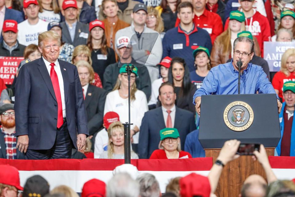 United States President Donald Trump listens as Republican senatorial candidate Mike Braun speaks during a rally at Southport Fieldhouse on Friday, Nov. 2, 2018. 