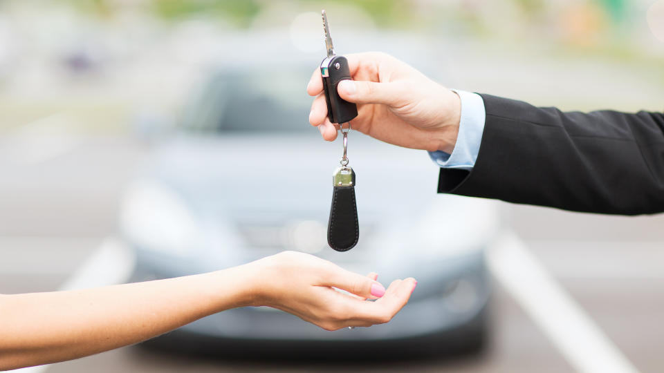transportation, business, rent and ownership concept - close up of customer and salesman hands with car key outside.