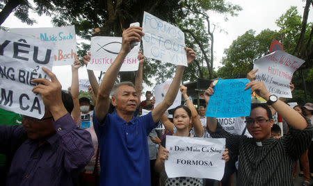 Demonstrators, holding signs to protest against Taiwanese enterprise Formosa Plastic and environmental-friendly messages, say they are demanding cleaner waters in the central regions after mass fish deaths in recent weeks, in Hanoi, Vietnam May 1, 2016. REUTERS/Kham