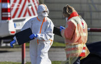 Workers of the fire department and the Red Cross take samples for coronavirus tests from car drivers at a mobile test station in Oberhausen, Germany, Tuesday, March 17, 2020. All public and private events are banned in Germany, clubs, bars restaurants and most shops are closed due to the virus outbreak. For most people, the new coronavirus causes only mild or moderate symptoms, such as fever and cough. For some, especially older adults and people with existing health problems, it can cause more severe illness, including pneumonia. (AP Photo/Martin Meissner)