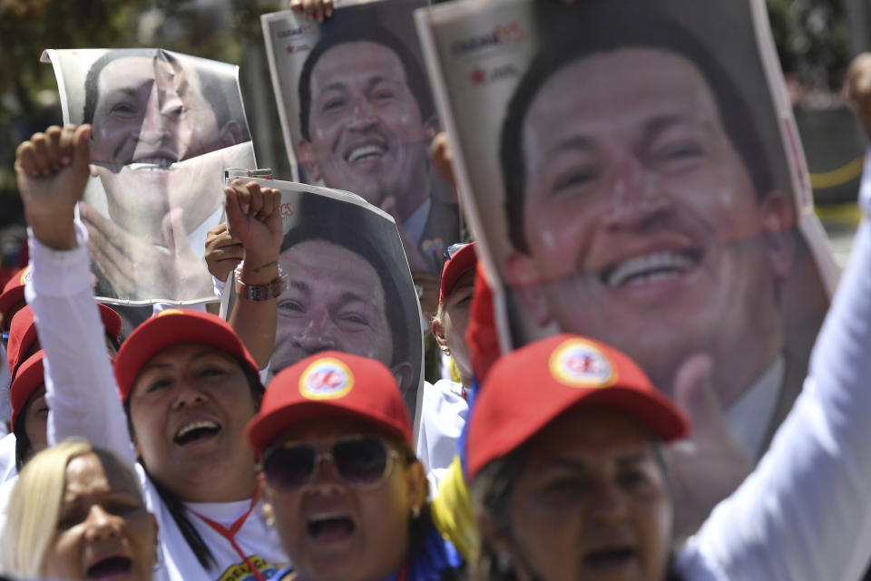 People hold posters with the image of late Venezuelan President Hugo Chavez during commemorations marking the tenth anniversary of his death, outside the Cuartel de la Montaña 4F where his remains are interred in Caracas, Venezuela, Sunday, March 5, 2023. Chavez died on March 5, 2013, after a long battle with cancer and chose current president, Nicolas Maduro, a former bus driver and union leader to be his successor. (AP Photo/Matias Delacroix)