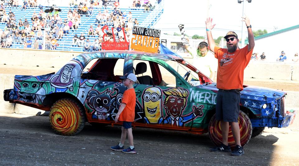 Craig Beaubien rallies the crowd with his son Beau, 6, while showing their demolition derby car during the Best of Show contest.