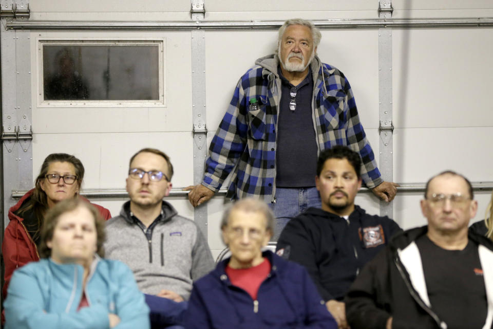 In this Oct. 24, 2019 photo, Bill Whitney, rear, listens at a town hall meeting at the fire hall in Winslow, Neb., where relocating the village was discussed. It took only minutes for swift-moving floods from the Elkhorn River to ravage tiny Winslow this spring, leaving nearly all its 48 homes and businesses uninhabitable. Now, the couple dozen residents still determined to call the place home are facing a new challenge: Moving the entire town about three miles away to higher ground. (AP Photo/Nati Harnik)