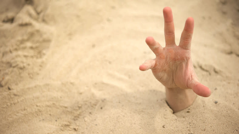 Hand stretching out of quicksand