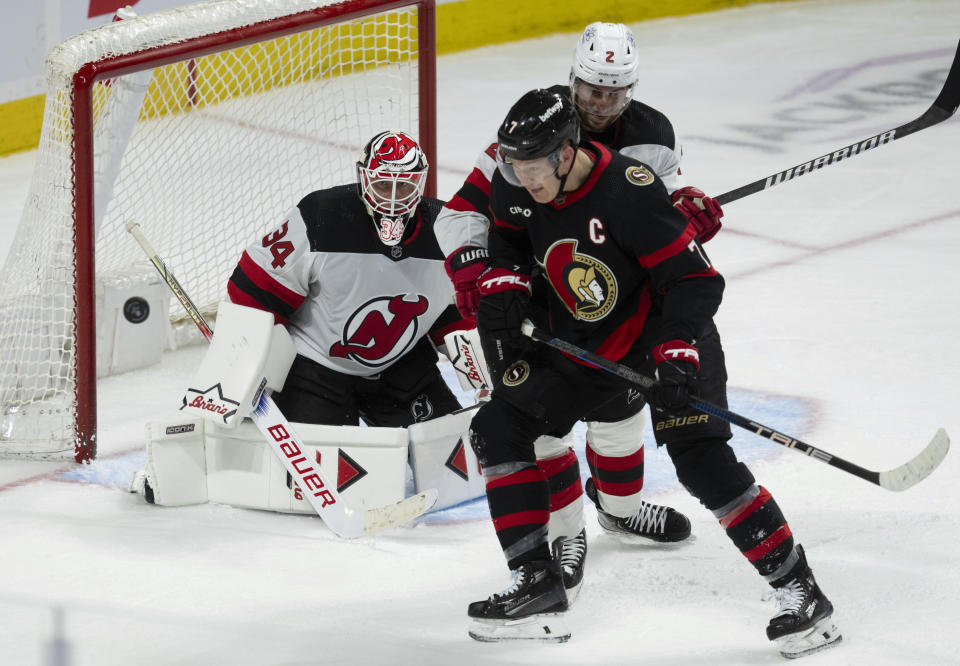 New Jersey Devils goaltender Jake Allen, left, watches the puck as defenseman Brendan Smith (2) battles with Ottawa Senators left wing Brady Tkachuk (7) in front of the net during third-period NHL hockey game action in Ottawa, Ontario, Saturday, April 6, 2024. (Adrian Wyld/The Canadian Press via AP)