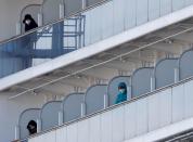 Pasajeros miran desde sus cabinas mientras el crucero Diamond Princess, donde 10 personas dieron positivo a las pruebas por coronavirus ayer, llega al Muelle para Cruceros Daikoku en Yokohama