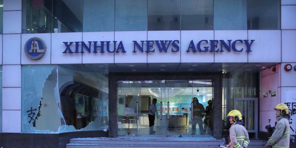 Firefighters stand outside the offices of China's Xinhua News Agency after its windows were shattered during protests in Hong Kong, Saturday, Nov. 2, 2019. Hong Kong riot police fired multiple rounds of tear gas and used a water cannon Saturday to break up a rally by thousands of masked protesters demanding meaningful autonomy after Beijing indicated it could tighten its grip on the Chinese territory. (AP Photo/Kin Cheung)