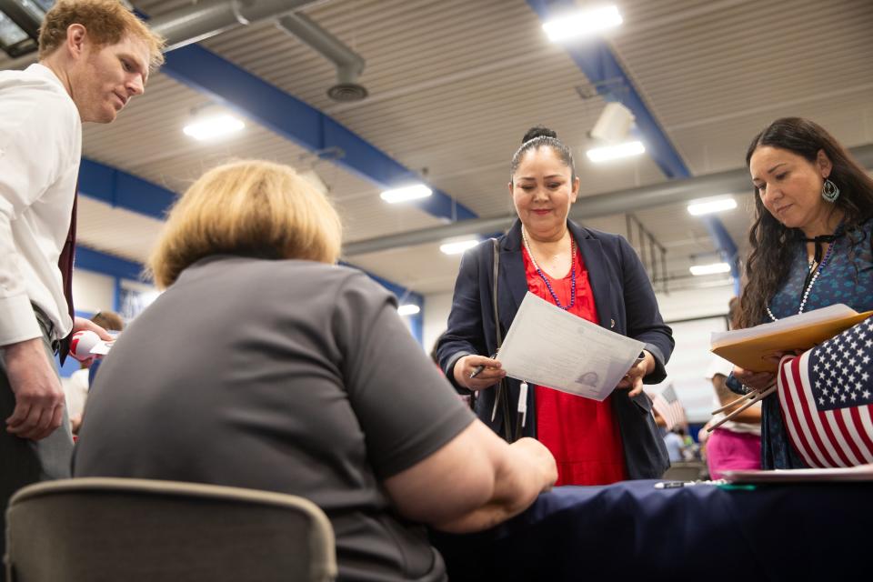 Miriam Mendoza hands in filled-out forms during a naturalization ceremony at South Mountain Community College in Phoenix on Tuesday, July 4, 2023.