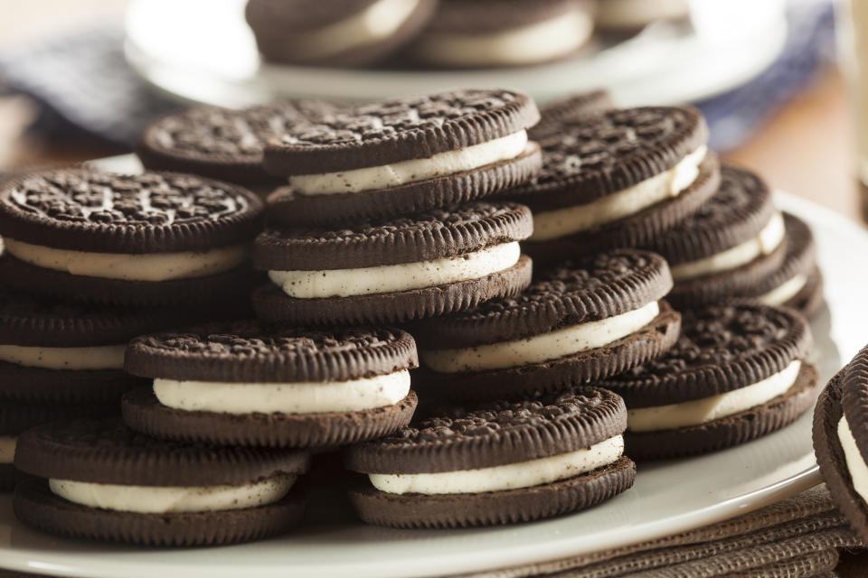 A plate piled high with chocolate cookies with cream fillings.