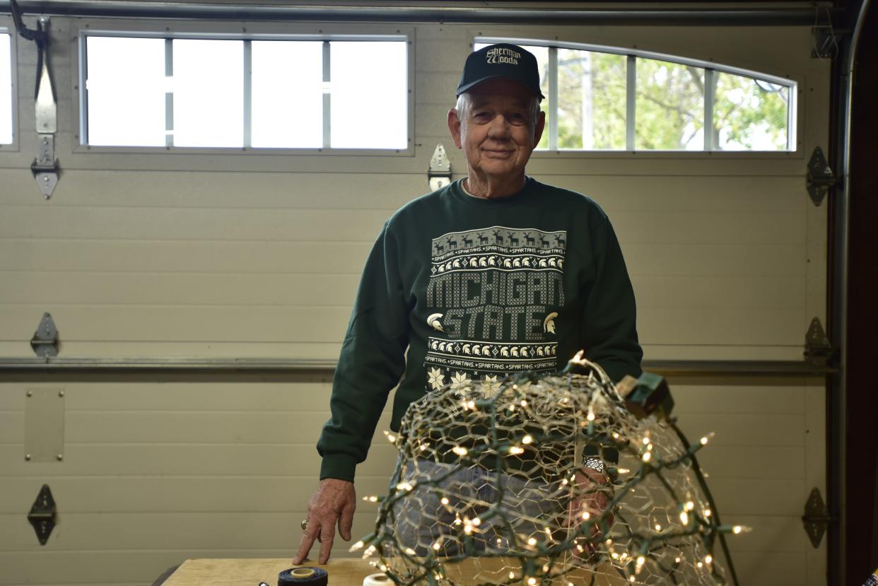 Sherman Woods Association president Fred Kemp demonstrates how to make the colorful Christmas decorations at the neighborhood on the northside of Port Huron on Thursday, Nov. 17, 2022. The colorful decorations are strung up in trees by neighbors every year to attract passerbys to leave a donation in a Salvation Army red kettle.