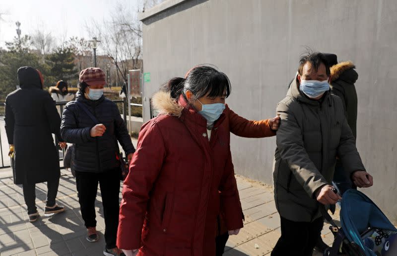 People wearing face masks walk along a street, following new cases of the coronavirus disease (COVID-19) in the country, in Beijing