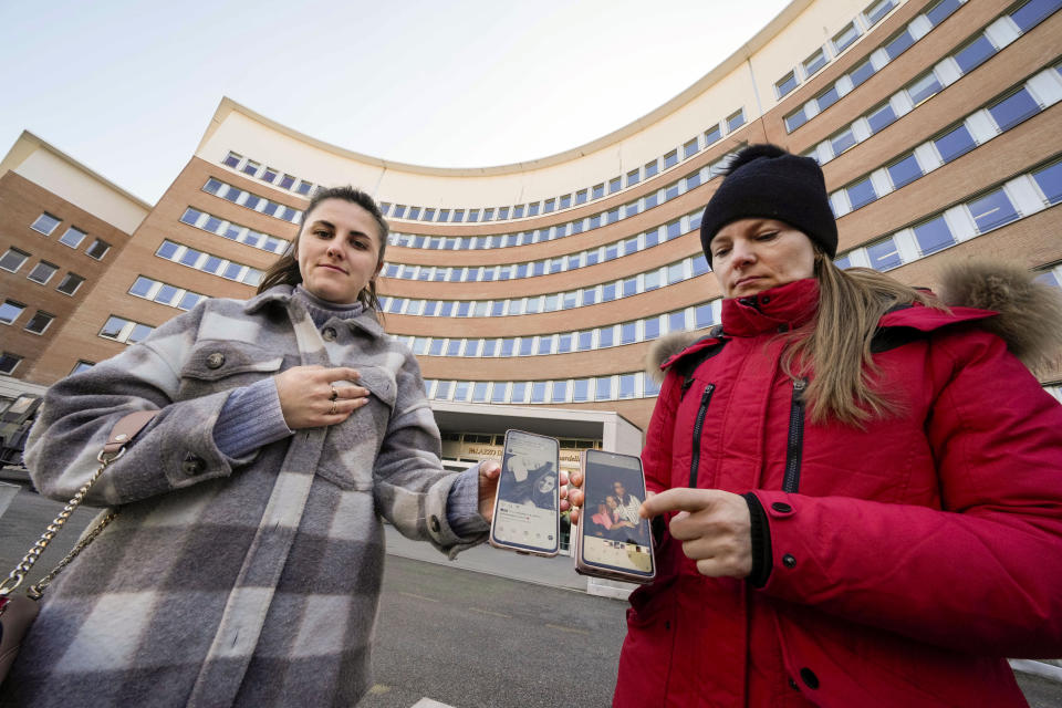 Verkalets Olha from Ukraine, right, and Veronica Catana of Moldova, show their smartphones with pictures of their Pakistani-born friend Sana Cheema before testifying in a trial about her alleged murder outside the courthouse in Brescia, northern Italy, Thursday, Feb. 9, 2023. The two women told the court how Cheema loved her Western lifestyle in Brescia and didn't want to go back to Pakistan, where her family wanted her to wed in an arranged marriage. An autopsy in Pakistan indicated Cheema was allegedly strangled. Brescia prosecutors alleged that Cheema's "political right" to marry whom she wanted was violated. (AP Photo/Luca Bruno)