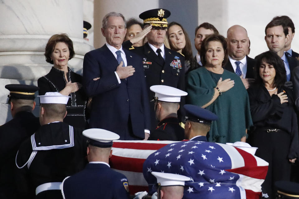 Former President George W. Bush, Laura Bush and other family members watch as a military honor guard carries George H.W. Bush's casket into the Capitol.