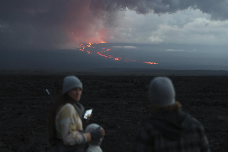 Spectators watch the lava flow down the mountain from the Mauna Loa eruption, Tuesday, Nov. 29, 2022, near Hilo, Hawaii. (AP Photo/Marco Garcia)