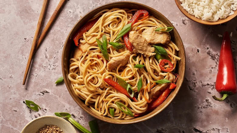 Bowl of lo mein next to chopsticks 