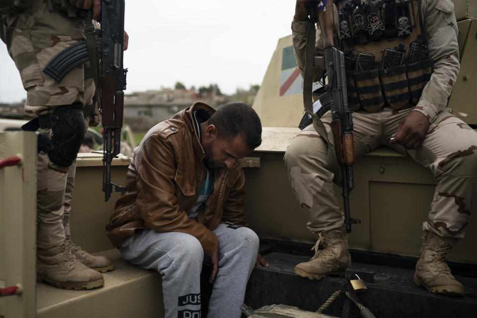 In this April 5, 2019 photo, a man is taken for questioning by Iraqi army 20th division soldiers during a raid in Badoush, Iraq. (AP Photo/Felipe Dana)