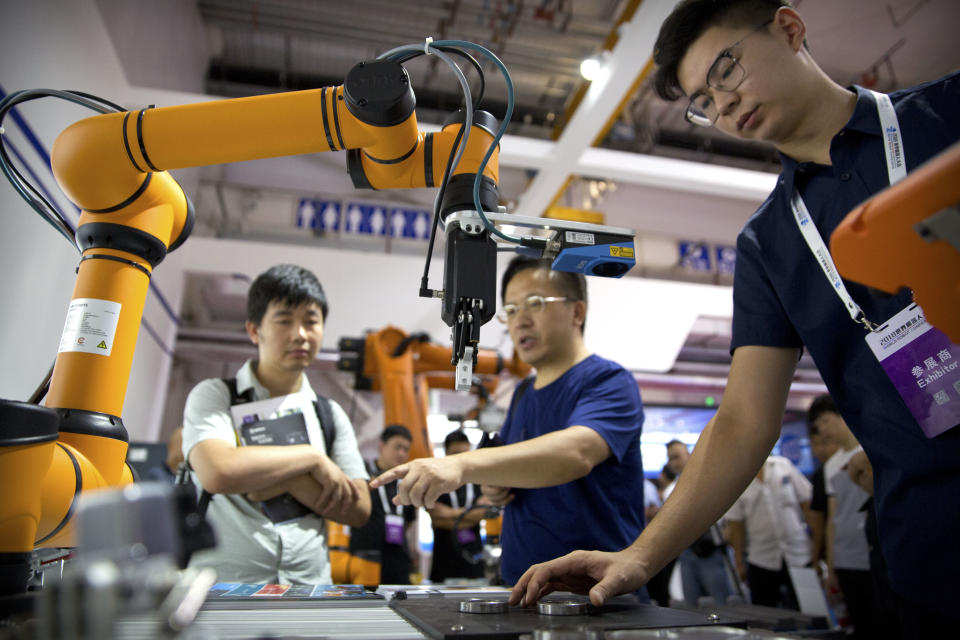 FILE - In this Aug. 18, 2018, file photo, visitors look at a manufacturing robot from Chinese robot maker Aubo Robotics at the World Robot Conference in Beijing, China. China’s government has appealed to Washington to accept its industrial progress after U.S. intelligence officials said Beijing helps to steal and copy foreign technologies. (AP Photo/Mark Schiefelbein, File)