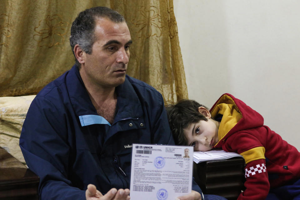 Faraj Ghazi al-Jamous, a Syrian refugee who was prevented from traveling to the U.S. because of the ban, sits in a living room with his son showing U.N. paperwork verifying his refugee status. (Photo: KHALIL MAZRAAWI via Getty Images)