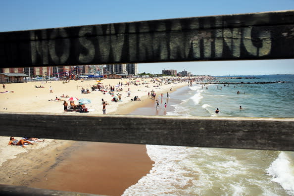 People enjoy the beach at Coney Island on July 12, 2012 in the Brooklyn borough of New York City. Coney Island has until recently been viewed as a seedy and dilapidating seaside park, however, it is going through a gradual transition which many compare to the renovation of Times Square. In order to accommodate more shops and residential buildings, the Michael Bloomberg administration rezoned Coney Island in 2009. The city also bought seven acres of prime Coney Island real estate promising approximately $150 million in infrastructure upgrades in the area. A recent study found that Coney Island's Luna Park had 640,000 visitors in 2011, the most since Steeplechase Park closed in 1964. (Photo by Spencer Platt/Getty Images)