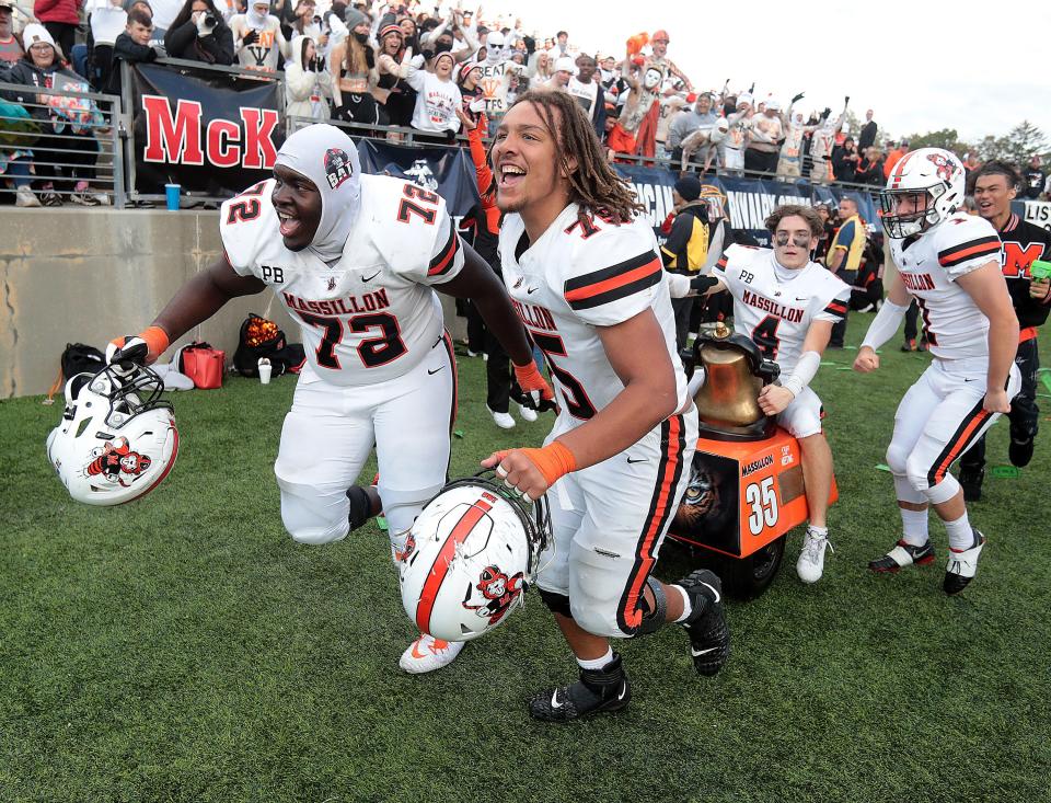 Massillon players from left, Te'Jamere Nash,and Lee Toddrick pull Austin Brawley as he rides the victory bell after beating McKinley Saturday, October 23, 2021.