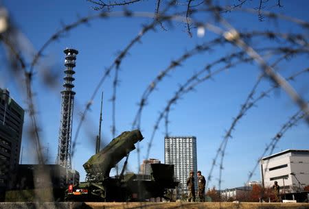 Members of the Japan Self-Defence Forces stand guard near Patriot Advanced Capability-3 (PAC-3) land-to-air missiles, deployed at the Defense Ministry in Tokyo, Japan, December 7, 2012. REUTERS/Issei Kato/File Photo