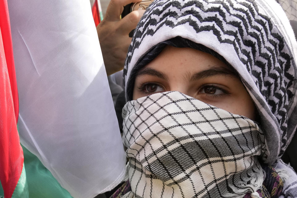 A Hezbollah supporter covers her face by a Palestinian Koufiya, during a protest to show their solidarity with the Palestinians, in the southern suburb of Beirut, Lebanon, Friday, Oct. 13, 2023. Tens of thousands of Muslims demonstrated Friday across the Middle East in support of the Palestinians and against Israeli airstrikes pounding Gaza, underscoring the risk of a wider regional conflict erupting as Israel prepares for a possible ground invasion in the coastal strip. The Arabic placard centre reads:"Gaza is the symbol of pride." (AP Photo/Hussein Malla)