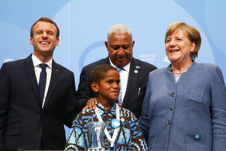 French President Emmanuel Macron, COP23 President Prime Minister Frank Bainimarama of Fiji and German Chancellor Angela Merkel pose for a photo with Timothy Naulusala from Fiji during the COP23 U.N. Climate Change Conference in Bonn, Germany, November 15, 2017. REUTERS/Wolfgang Rattay