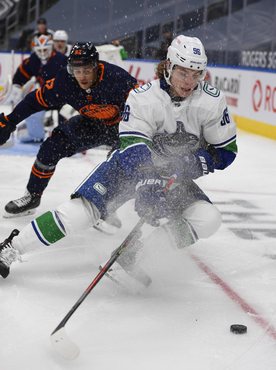 Edmonton Oilers' Caleb Jones (82) chases Vancouver Canucks' Adam Gaudette (96) during the third period of an NHL hockey game Wednesday, Jan. 13, 2021, in Edmonton, Alberta. (Dale MacMillan/The Canadian Press via AP)