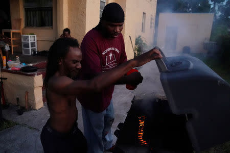 People cook on an open fire after Hurricane Irma hit in the Little Haiti neighborhood of Miami, Florida, U.S., September 12, 2017. REUTERS/Carlo Allegri