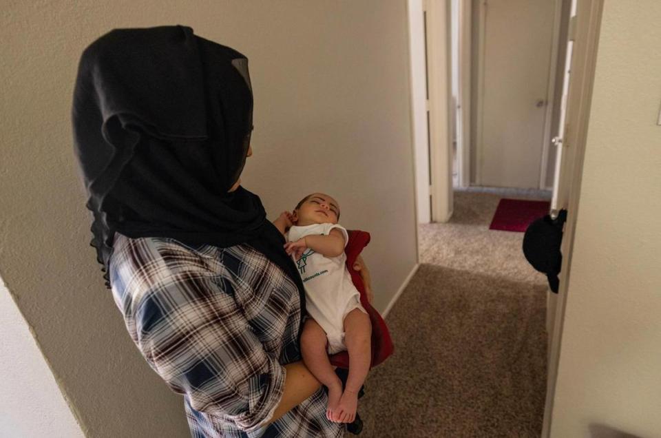 Aziza, an Afghan refugee who fled her country when the Taliban took over in 2021, holds her sleeping baby in her apartment in Fort Worth. Aziza asked Angie Kraus to help supply her with a bed for her baby as she begins to get settled in her new home.