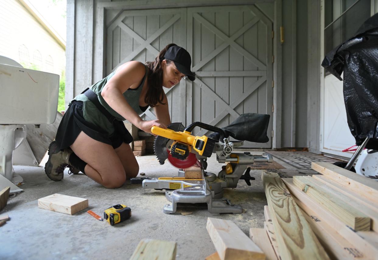 Claire Buitendorp of Grand Ledge uses a chop saw as she and twin sister Shawn work on a bathroom remodeling project for Lakeland Remodeling Wednesday, June 5, 2024, in Grand Ledge. She and twin sister Claire are implementing their design skills and experience in the remodeling trade.