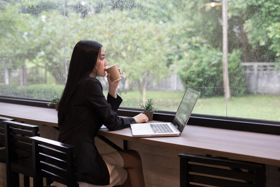 Businesswoman Drinking Coffee While Sitting At Desk In Office