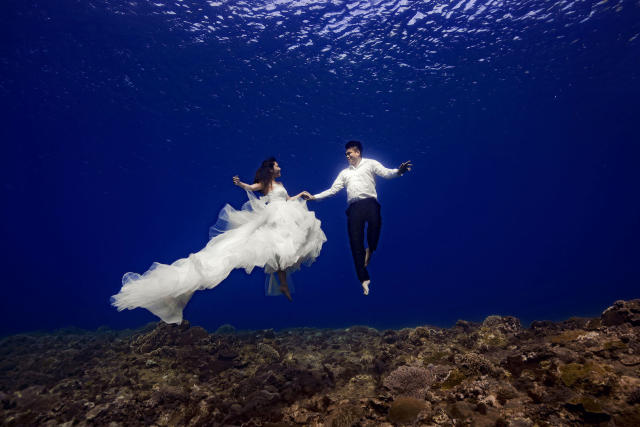 Bride and groom pose for underwater wedding shoot