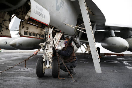 A U.S. Navy crew member works on a U.S. F18 fighter jet on the deck of U.S. aircraft carrier USS Carl Vinson during an annual joint military exercise called "Foal Eagle" between South Korea and U.S., in the East Sea, South Korea, March 14, 2017. REUTERS/Kim Hong-Ji