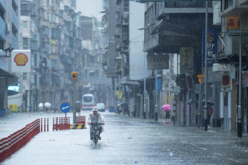 In this photo released by China's Xinhua News Agency, a man rides a bicycle during a rainstorm in Macao, Wednesday, Aug. 19, 2020. China faced a double whammy Wednesday of flooding and landslides from unusually heavy seasonal rains and a typhoon that came ashore on its southern coast. (Cheong Kam Ka/Xinhua via AP)