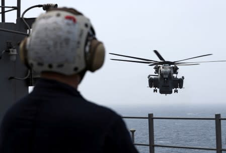 A U.S. Navy officer watches as CH-53E Super Stallion aircraft attempts to land on the USS Boxer (LHD-4) in the Arabian Sea off Oman