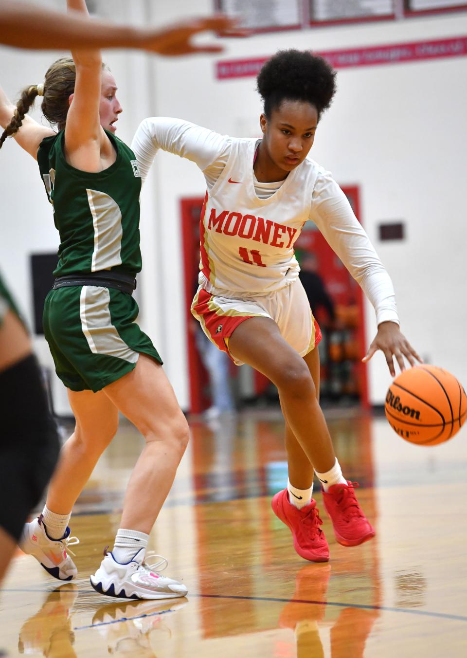 Mooney's Bri Behn (#11) drives past Tampa Catholic defender Emily Martelli (#12) . Cardinal Mooney hosted Tampa Catholic in the girls basketball regional semi-final on Tuesday night. 