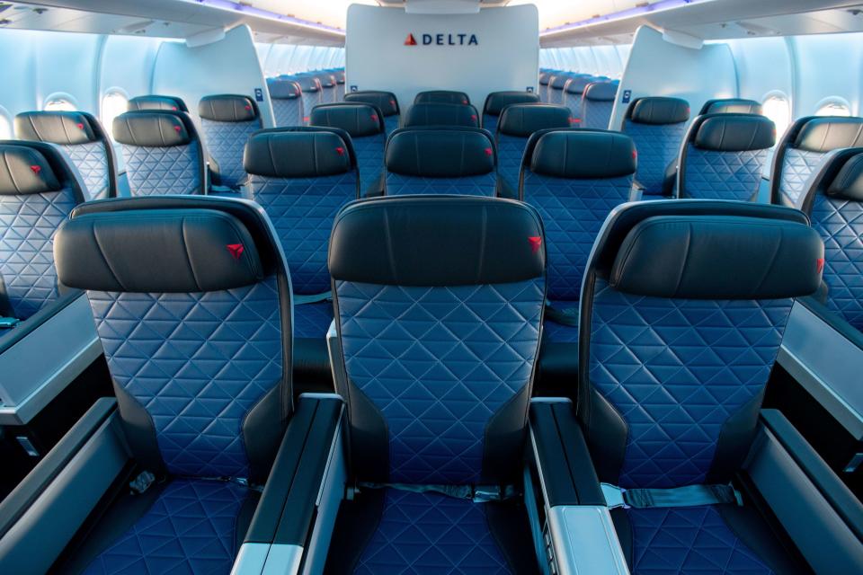 Looking over rows of Delta Premium Select international premium economy seats towards a Delta logo on board an Airbus A330-900neo.