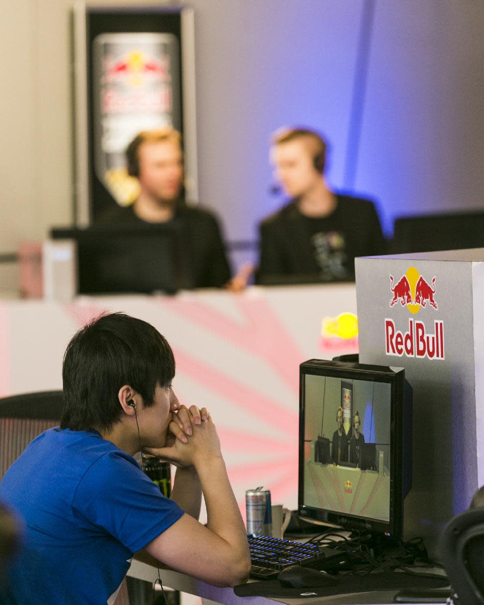 In this photo taken Friday, June 21, 2013, legendary "WarCraft 3" player, Jo "Golden" Myeong Hwan, from South Korea, left, listens to casters Sean “Day[9]” Plott, and Mike “Husky” Lamond at the Red Bull Training Grounds, held at Red Bull North America headquarters in Santa Monica, Calif. The Red Bull TV e-sports series included live-streamed scrimmages and a tournament with $8,600 in prize money. (AP Photo/Damian Dovarganes)