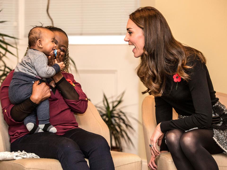 Kate Middleton chats with another mom and smiles at a baby.