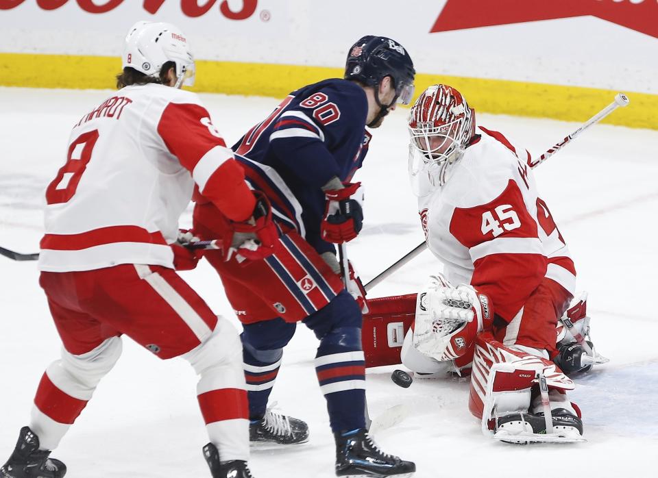 Winnipeg Jets' Pierre-Luc Dubois (80) cannot get his shot past Detroit Red Wings goaltender Magnus Hellberg (45) as Red Wings' Ben Chiarot (8) defends during second-period NHL hockey game action in Winnipeg, Manitoba, Friday, March 31, 2023. (John Woods/The Canadian Press via AP)